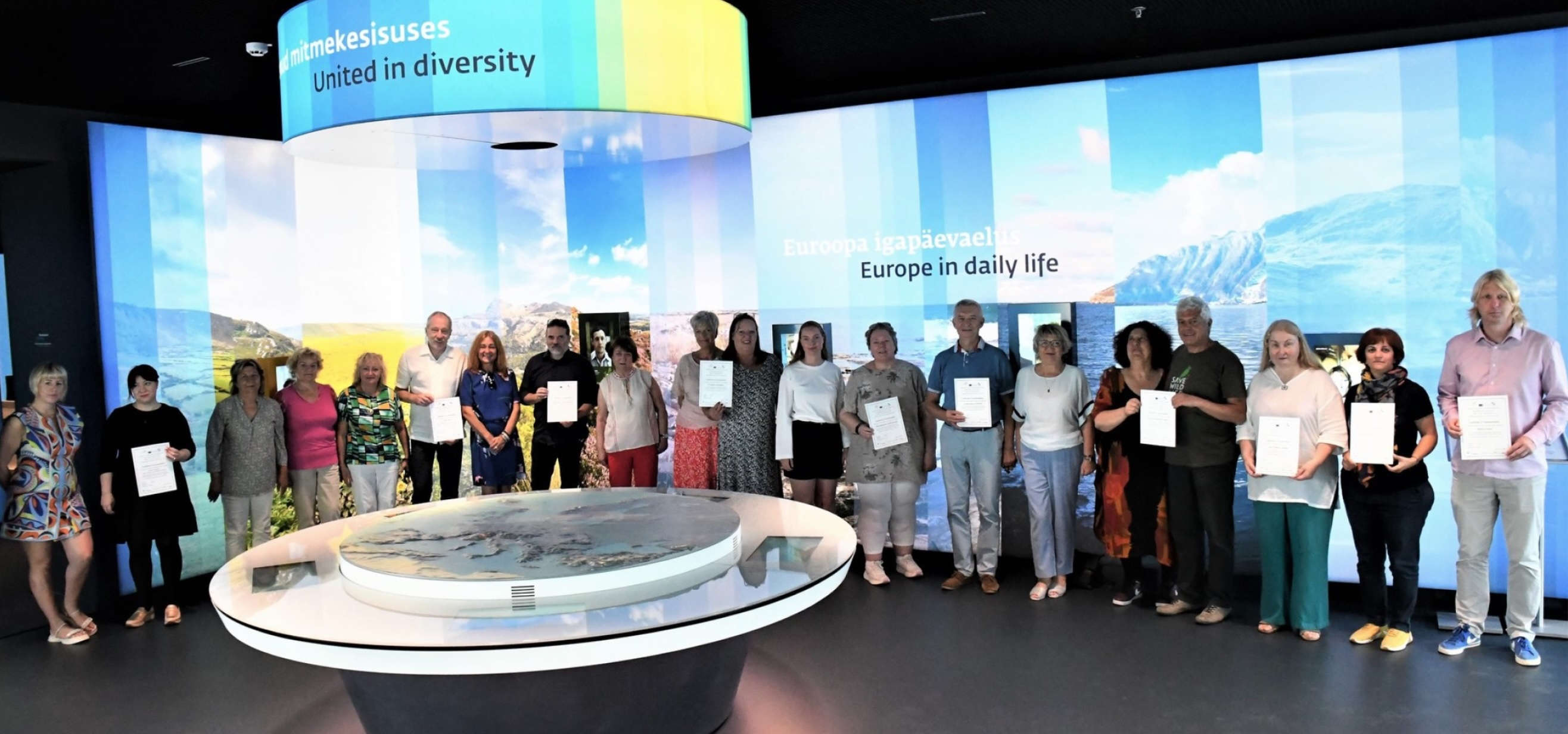 Group photo of diverse participants in front of a 'United in diversity' display